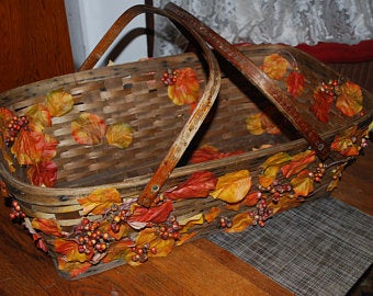 This is a wicker basket decorated with Autumn branches, leaves, and berries created by Marnie Lewens in 2018.